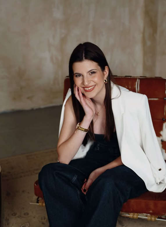 Portrait of Mina Gvozdenov, smiling, seated on a leather chair